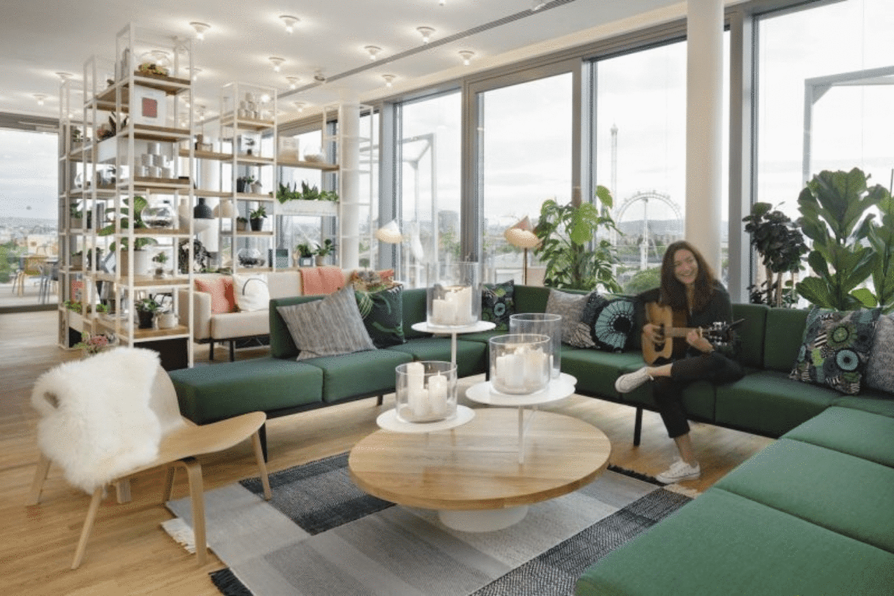 Spacious living room with a large green sofa, girl with guitar on the sofa