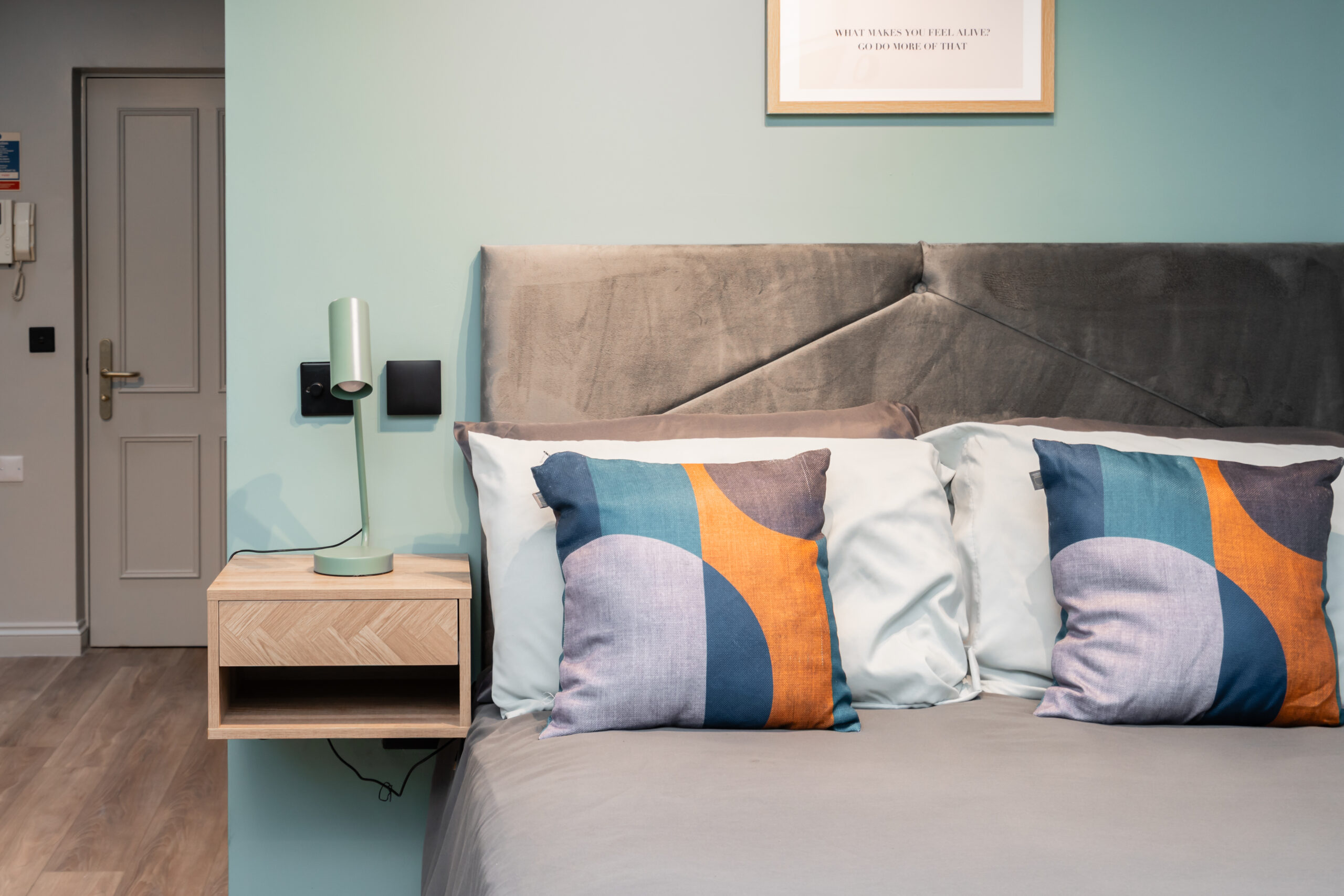 Comfortably dressed bed with modern headboard and nightstand, highlighting move-in bedroom essentials