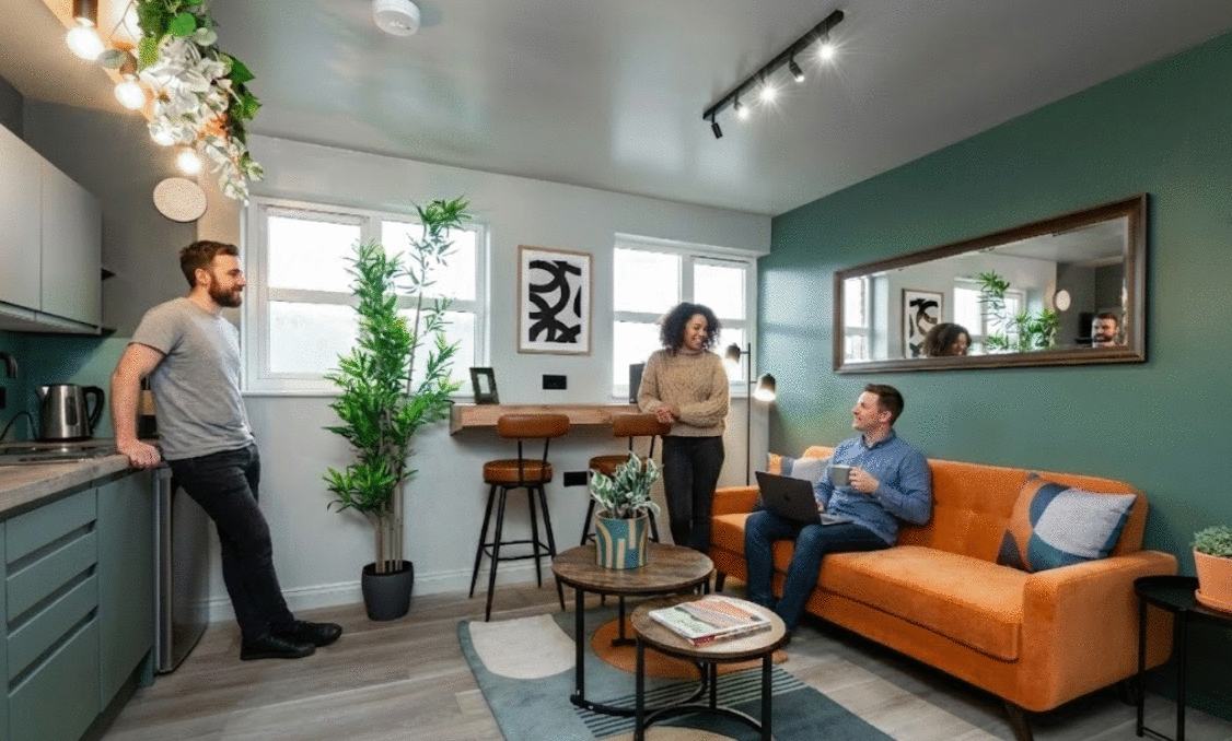 Remote worker on laptop in modern coliving living room, thriving in car-free Bicester
