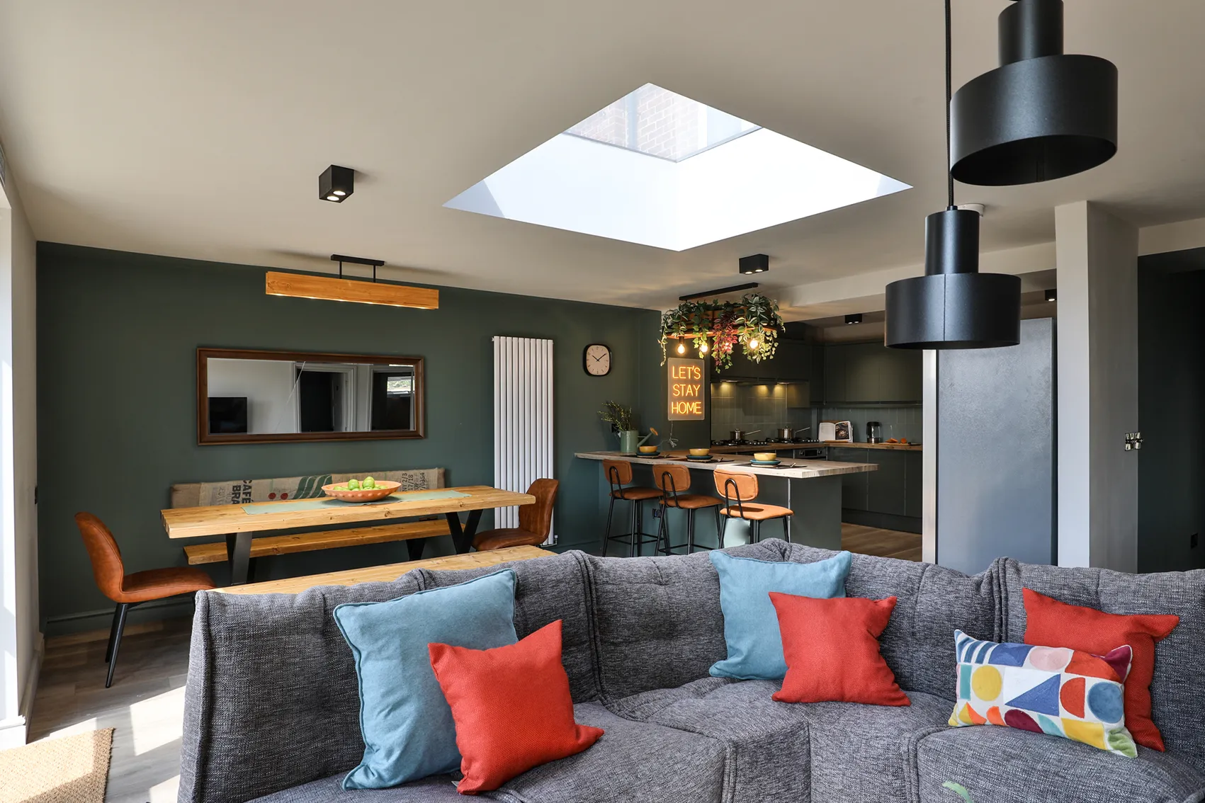 Expansive open-plan communal living and dining area with skylight and corner sofa, fostering community and connection