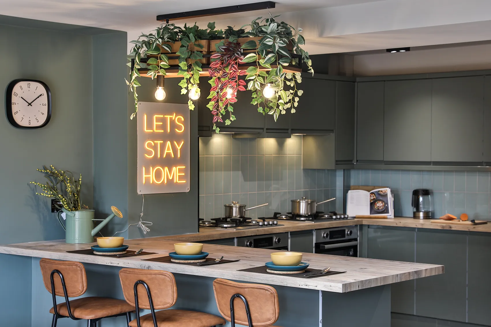 Co-living kitchen and breakfast bar with 'Let's Stay Home' neon sign, designed for spontaneous conversations and shared meals